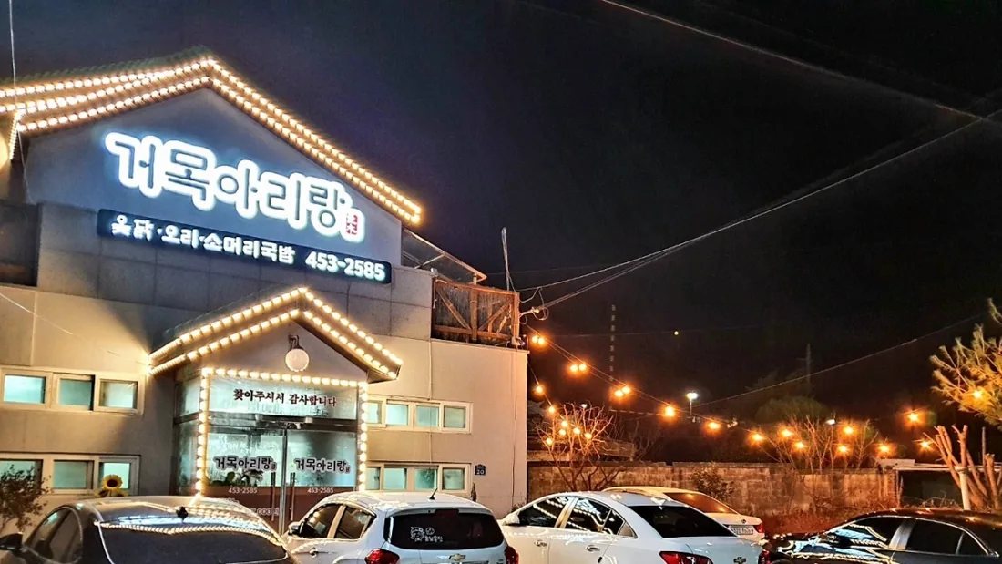 저녁에 불을 켠 거목아리랑 외관과 도로변 간판